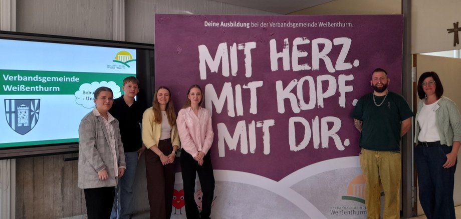 Vor dem Banner der VG stehen die Kolleginnen und Kollegen, die die Verwaltung präsentiert haben.