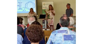 Vortrag Wasser pflanzen Foto 2 Heike Boomgaarden und Werner Ollig stehen mit VG-Touristikerin Lena Beck vor der Präsentation und vor dem Publikum.