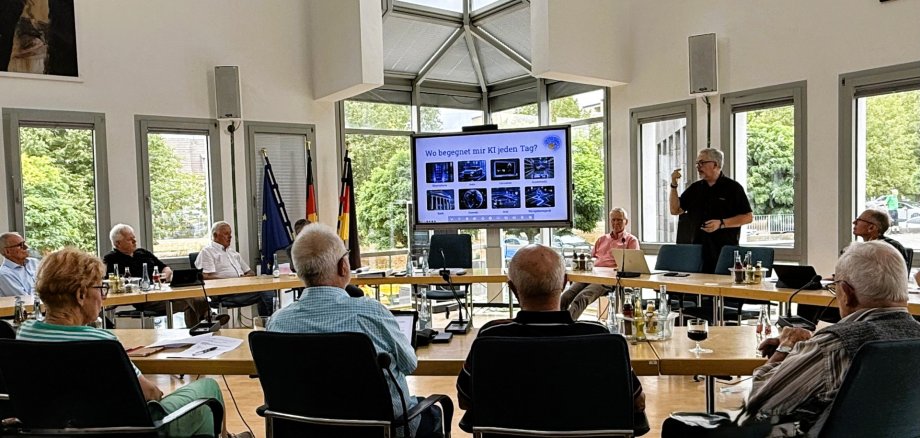Der Seniorenbeirat tagt im Ratssaal, vorne steht Referent Jörg Eisbach und hält einen Vortrag. 