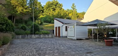 Im rückwärtigen Teil des Fachwerkhauses sind  im Hof Tische und Stühle unter einem Pavillon und einem Sonnenschirm aufgestellt, außerdem ein Eiscontainer und ein Toilettenhäuschen. 