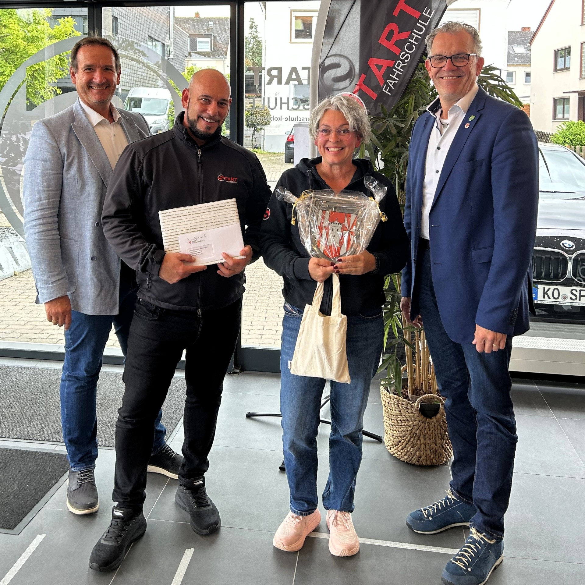 Eröffnung START Fahrschule VG-Bürgermeister Thomas Przybylla und der Mülheim-Kärlicher Stadtbürgermeister Gerd Harner stehen mit Fahrschulinhaberin Alexandra Löhr und einem Fahrlehrer in der neuen Fahrschule.