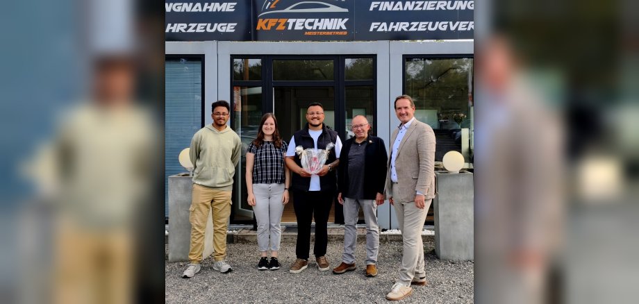 Besuch SMZ Foto VG-Bürgermeister Thomas Przybylla, Stadtbürgermeister Johannes Juchem, Unternehmer Dogukan Sarsilmaz, Wirtschaftsförderin Alina Kneip und ein Gast-Azubi stehen vor dem neu eröffneten Gebrauchtwagenhandel.