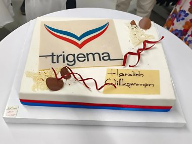 Auf einem Stehtisch steht eine Torte mit trigema-Logo.