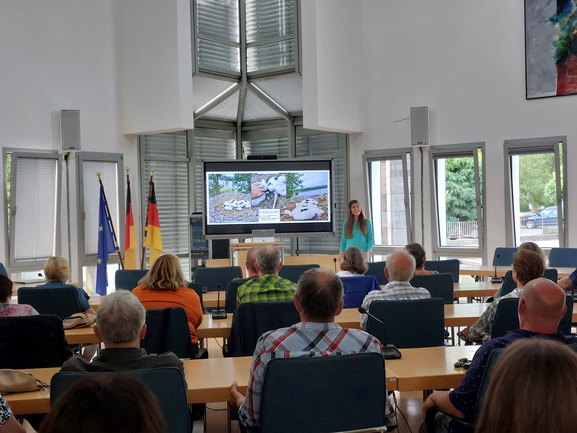 Vortrag Störche Foto Publikum 1 Die Referentin steht vor dem Bildschirm, davor sitzt das Publikum.