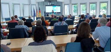 Vortrag Störche Publikum Foto 2 Im Ratssaal sitzt das Publikum, im Hintergrund die Referentin vor ihrer Präsentation.