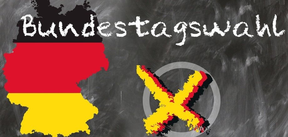Auf einem grauen Untergrund ist links der Umriss der Bundesrepublik in den Farben Schwarz, rot und gelb zu sehen, rechts daneben ein weißer Kreis mit einem gelben Kreuz, darüber der Schriftzug Bundestagswahl. 