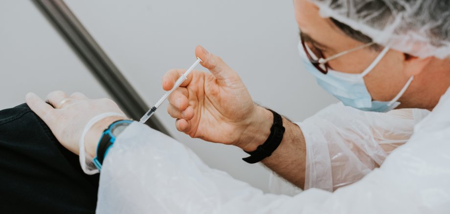 Ein Artzt gibt dem Patientin eine Impfung. 