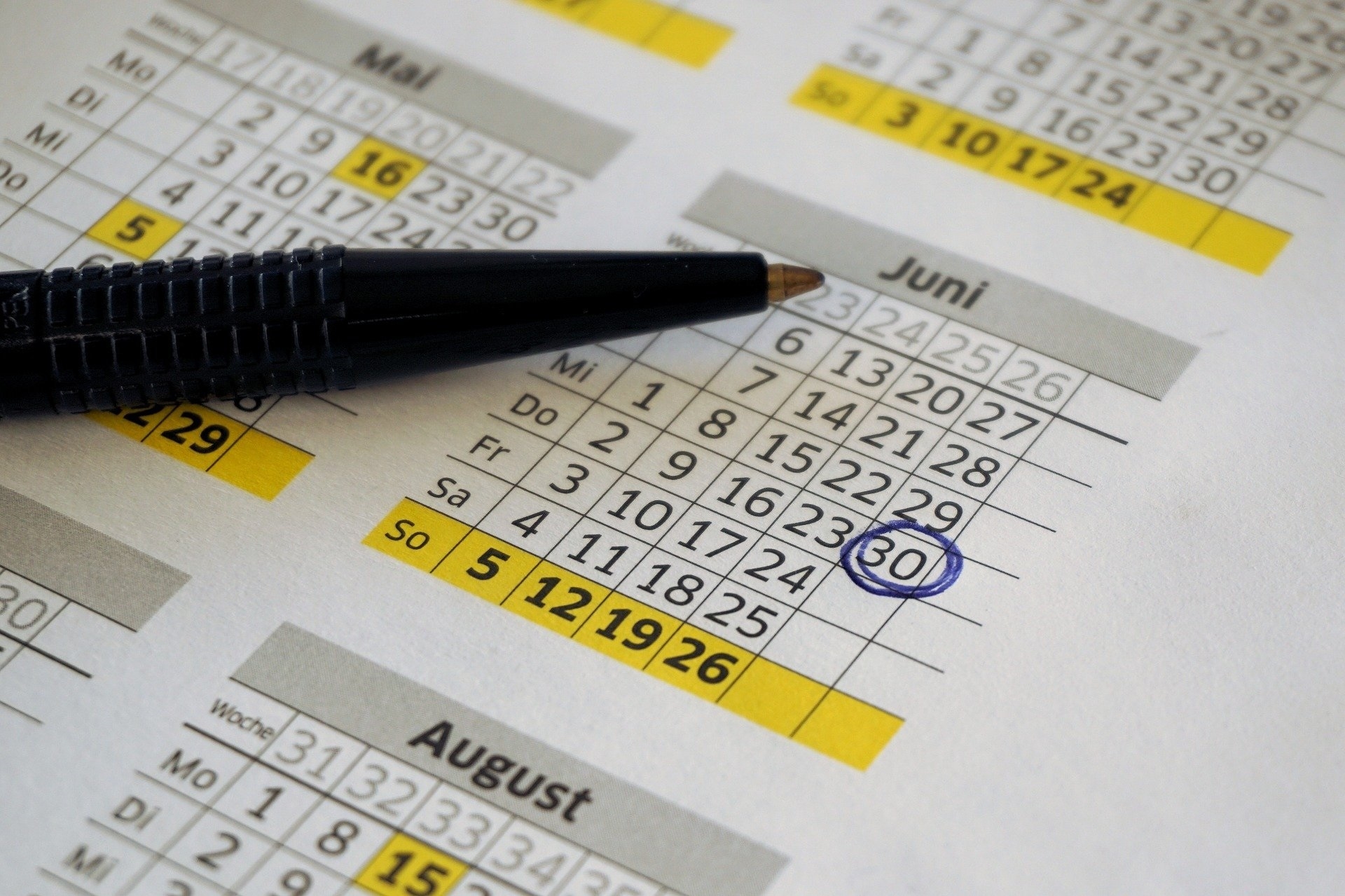 Auf dem Kalender liegt ein schwarzer Kugelschreiber womit ein schwarzes Kreuz gemacht wurde. 