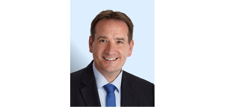 Porträtfoto Thomas Przybylla mit hellblauem Hintergrund.