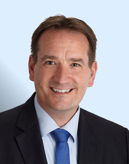 Porträtfoto Thomas Przybylla mit hellblauem Hintergrund.