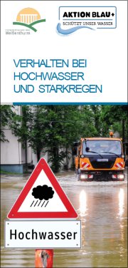 Die Titelseite des Flyers zur Hochwasservorsorge zeigt eine überflutete Straße, ein orangefarbener LKW, der durch das tiefe Wasser fährt und im Vordergrund ein Warnschild Hochwasser.